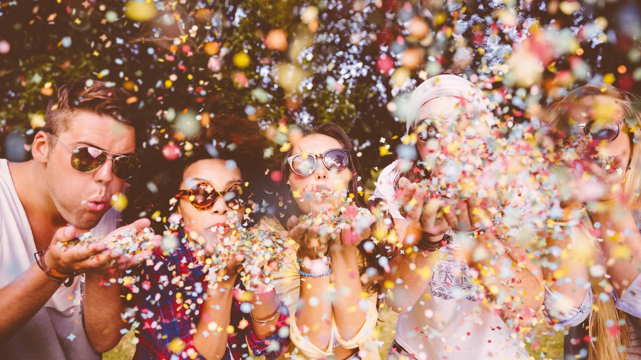 Hipsters blowing confetti; image used for earning online spending rewards with integrated account.