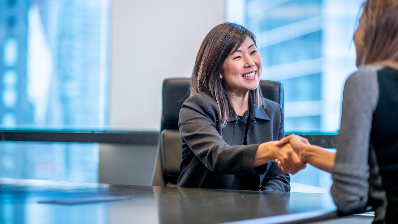 A business-woman shaking hand with her client; image used for account services.