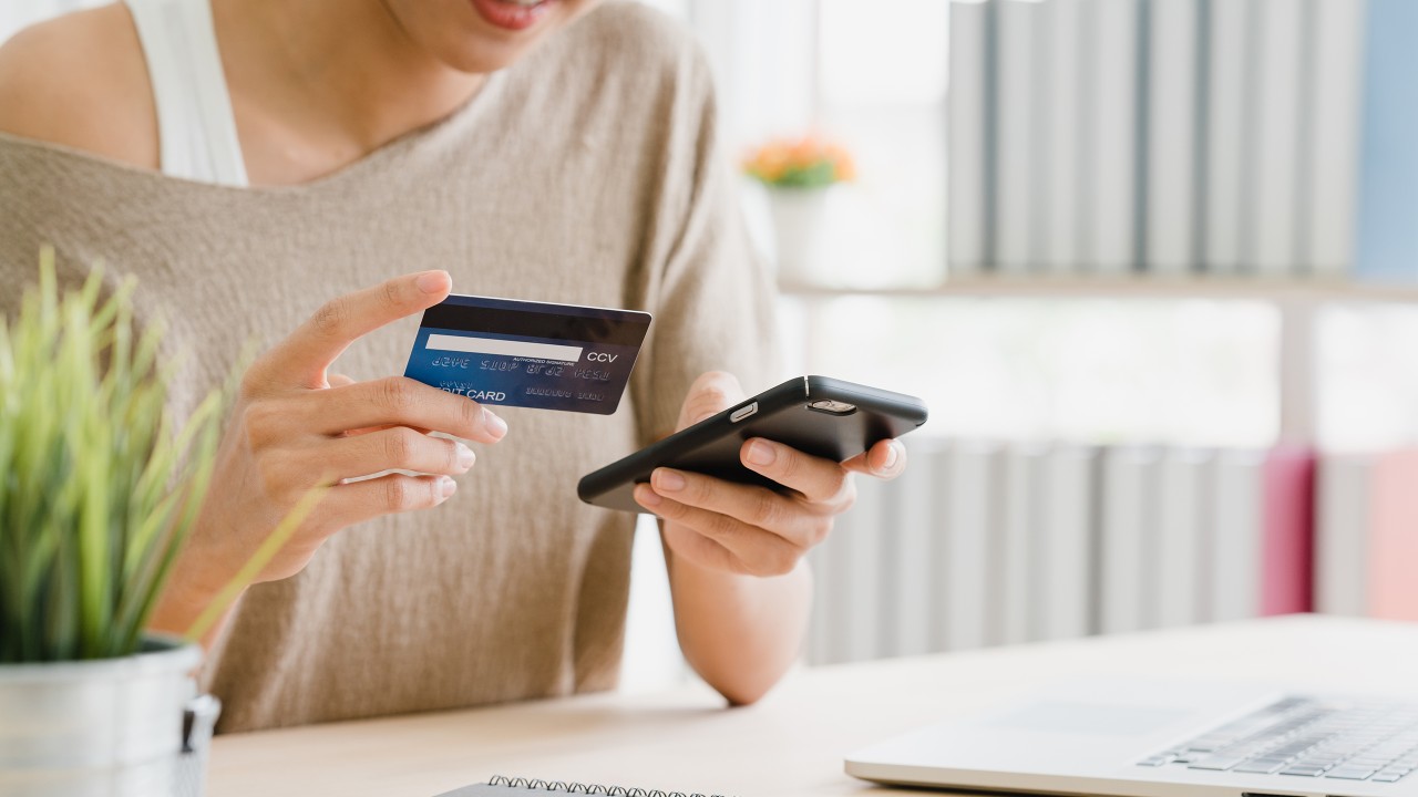 一位女士正在使用她的手机支付信用卡；图片使用于汇丰信用卡。