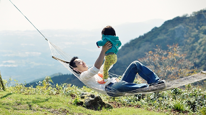A father is holding his child in hammock; image used for HSBC Life Insurance.  