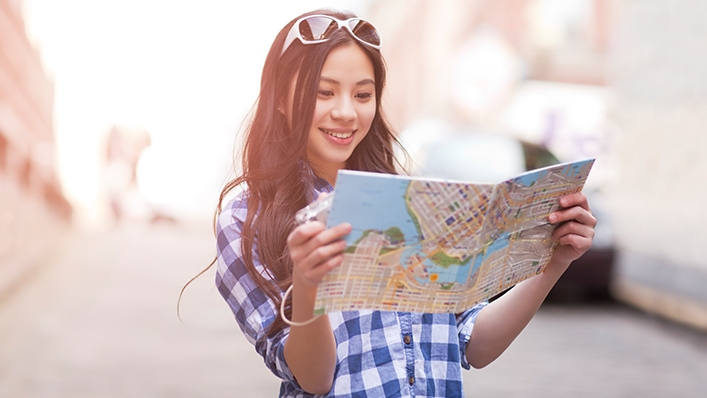 A girl is reading a map; image used for HSBC Travel Insurance.