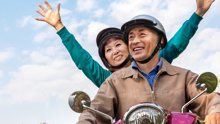 一对年迈夫妇兴奋地骑着电单车；图片使用于汇丰盈达延期年金计划页面。