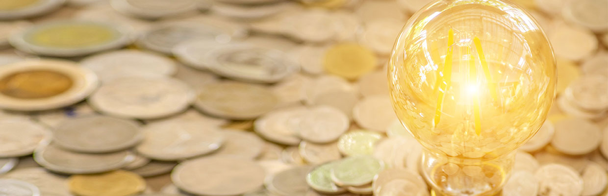 Light bulb and pile of coins; image used for gold trading services.