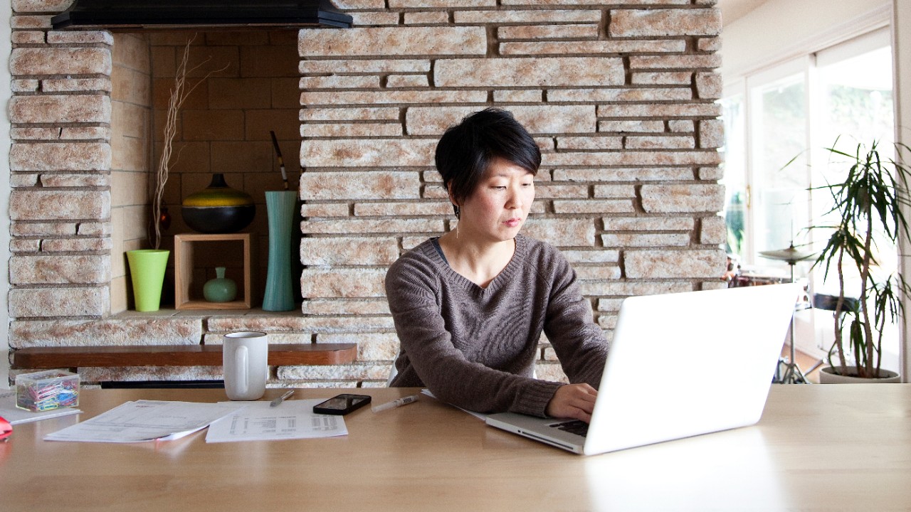 A woman is making a funds transfer from her laptop at home; image used for HSBC autoPay